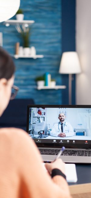 Student having online videcall conference with physician doctor consulting about healthcare treatment. Patient woman using laptop computer for medical consulatation while sitting in living room